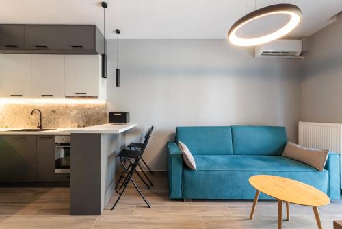 a living room with a blue couch and a kitchen at Hippocrates bound by BiNoBi! in Thessaloniki