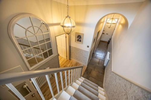 a hallway with a staircase with a mirror and a chandelier at Porte House - Holiday At Home in Richmond
