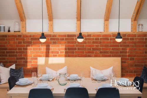 een tafel in een kamer met een bakstenen muur bij The Aston - Superbly Equipped 4 Bedroom Townhouse in Henley on Thames