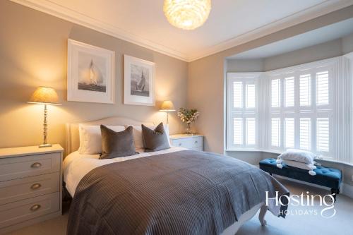 a bedroom with a bed and two windows and a chandelier at The Aston - Superbly Equipped 4 Bedroom Townhouse in Henley on Thames