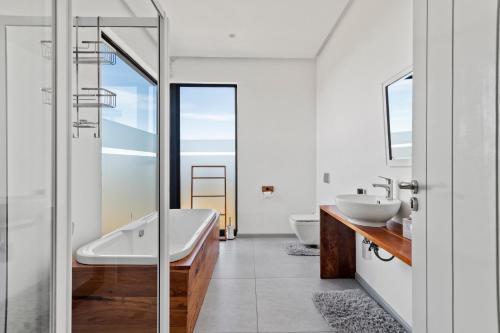 een badkamer met 2 wastafels, een bad en een douche bij Romansbaai Moksha on the Sea in Gansbaai