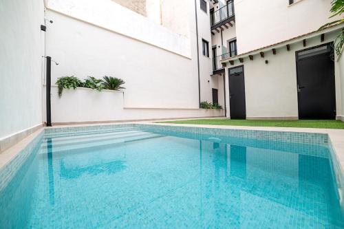 a swimming pool in a building with blue water at Apartamentos Loliqui centro Alicante in Alicante