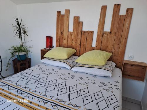 a bed with a wooden headboard and two pillows at Cap Esterel vue Mer in Agay - Saint Raphael