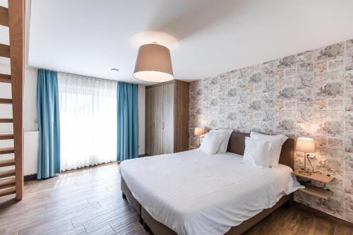 um quarto com uma grande cama branca e uma parede de tijolos em B&B Orgel Thuis em Kinrooi