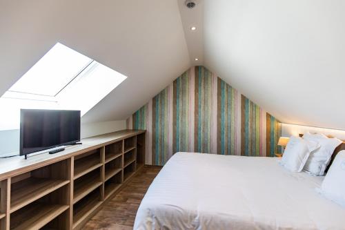 a attic bedroom with a bed and a television at B&B Orgel Thuis in Kinrooi