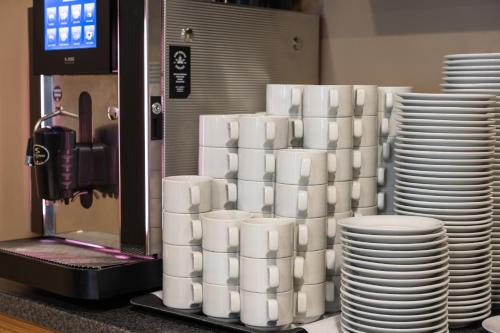 a stack of white cups and plates next to a machine at Bellevue Park Hotel Riga with FREE Parking in Rīga