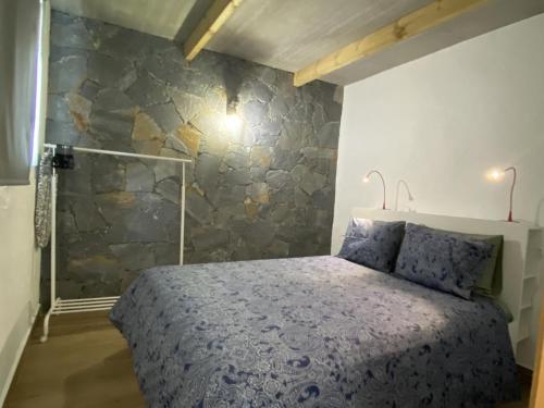 1 dormitorio con cama y pared de piedra en Casa de La Maceta, en La Frontera