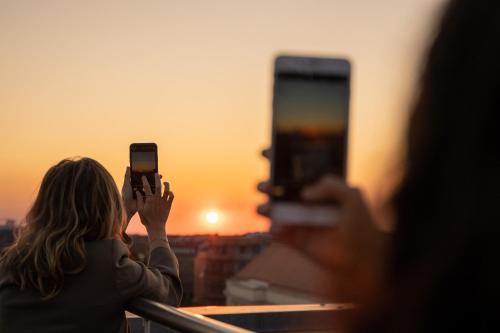 two people taking pictures of the sunset with their cell phones at INNSiDE by Meliá Leipzig in Leipzig