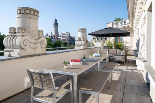 a rooftop patio with tables and chairs on a building at INNSiDE by Meliá Leipzig in Leipzig