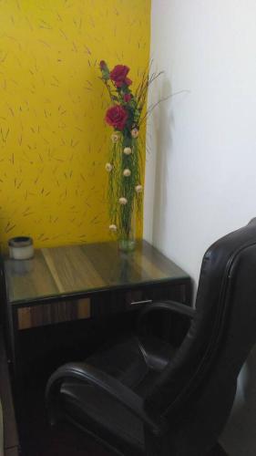 a desk with a vase of flowers and a chair at Moydom Nice & Cosy Private 1 BHK Apartment OPP NFC market in New Delhi