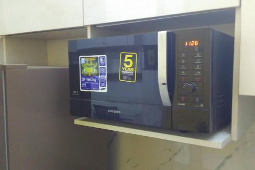 a microwave oven on a shelf in a kitchen at Moydom Nice & Cosy Private 1 BHK Apartment OPP NFC market in New Delhi