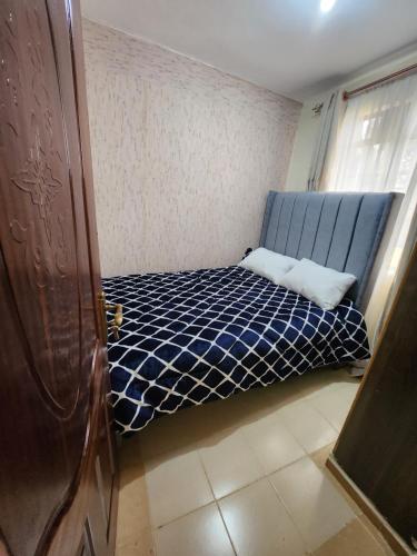 um pequeno quarto com uma cama azul num quarto em Zuri homes 1 em Kagio
