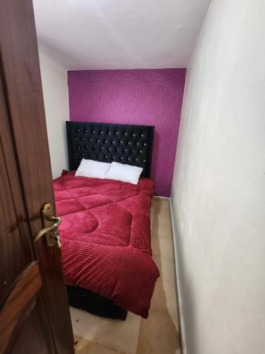 una camera con letto rosso e pareti viola di Zuri homes 1 a Kagio