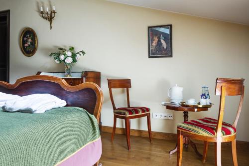 a bedroom with a bed and two chairs and a table at Burbiskio dvaras in Anykščiai