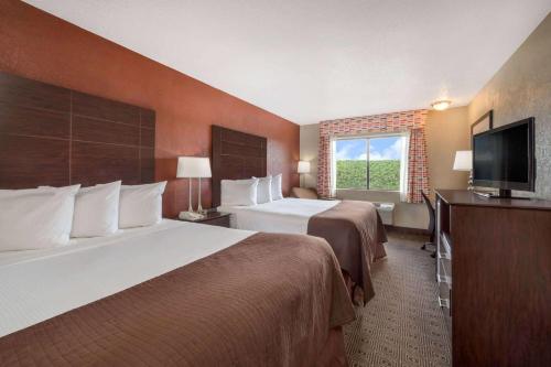 a hotel room with two beds and a flat screen tv at Baymont by Wyndham Midland Airport in Midland