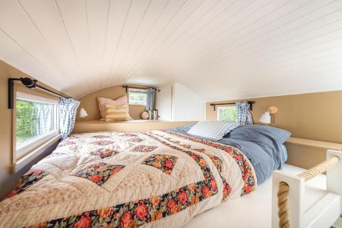 a bedroom with a bed and two windows at Fleur de Grog - Shepherds Hut in Bodmin