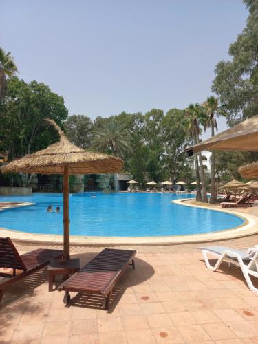 een zwembad met stoelen, een parasol en een tafel bij Tunisia Lodge in Hammamet