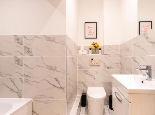 a white bathroom with marble walls and a sink and a toilet at King's House by Smart Apartments in Southampton
