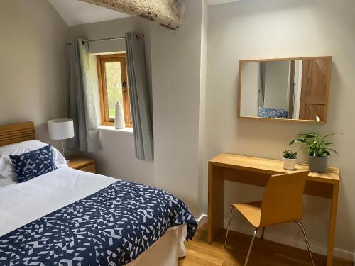 a bedroom with a bed and a desk and a mirror at Two bed barn in Henley in Arden