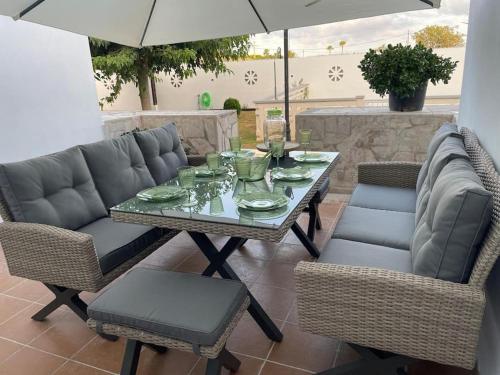 una mesa, sillas y una sombrilla en el patio en Adosado Vinaròs en Vinarós