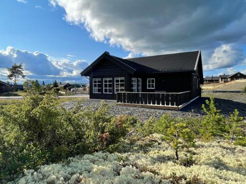 a black house with a black roof at Tisleibu - cabin at Golfjellet in Tisleidalen