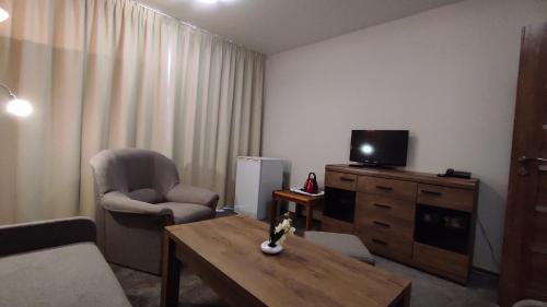 a living room with a tv and a chair and a table at Hotel SOREA ĽUBOVŇA in Stará Ľubovňa