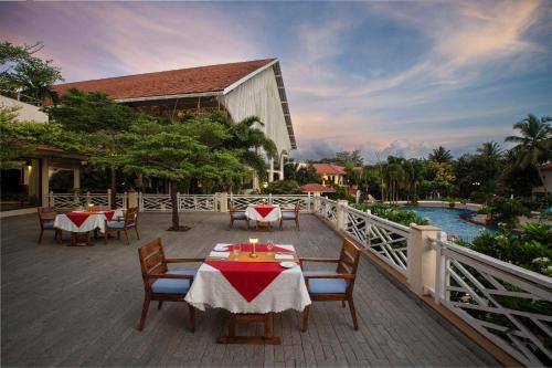 a patio with tables and chairs and a pool at Radisson Blu Resort, Goa in Cavelossim