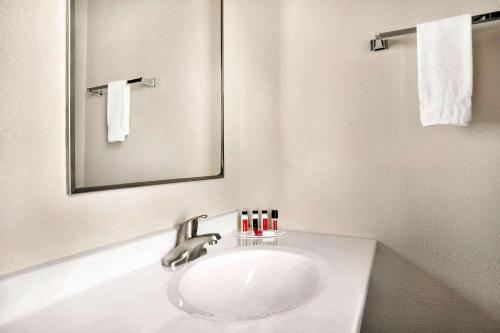 W białej łazience znajduje się umywalka i lustro. w obiekcie Travelodge by Wyndham Edgemont w mieście Edgemont
