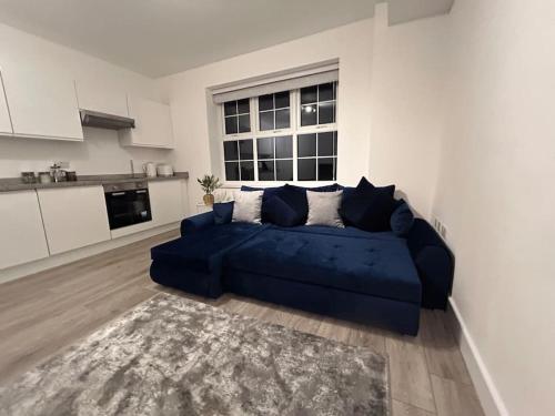 a blue couch in a living room with a kitchen at 1 bed high quality modern flat in Edgware