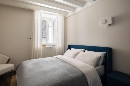 a bedroom with a bed with a blue headboard and a window at Maison MUSA at Vita B in Lenno