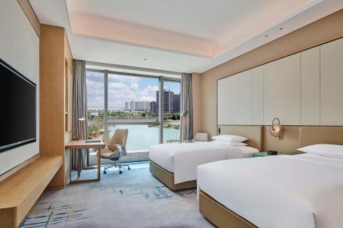 una camera d'albergo con due letti e una televisione di Doubletree By Hilton Suzhou Wuzhong a Suzhou