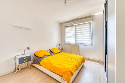 ein Schlafzimmer mit einem Bett mit gelber Bettwäsche und einem Fenster in der Unterkunft Le St Gratien - Appartement avec jardin in Épinay-sur-Seine