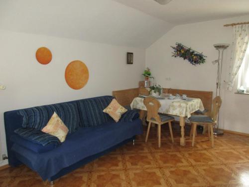 sala de estar con sofá azul y mesa en Gästehaus Reisacher - Mehrbettzimmer, en Peiting