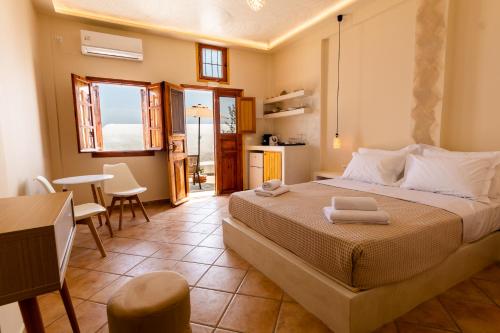 a bedroom with a bed and a kitchen and a table at Ostria Caldera Studios in Oia