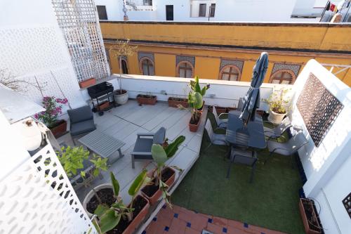 einen Blick über eine Terrasse mit Stühlen und einem Sonnenschirm in der Unterkunft The Terrace, dúplex con terraza privada in Sevilla