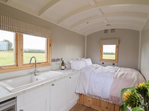 um quarto com uma cama, um lavatório e janelas em Shepherds Hut em Scunthorpe
