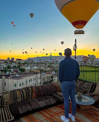 a person standing on a balcony looking at hot air balloons at Lord of Cappadocia Hotel in Goreme
