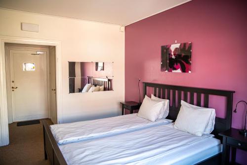 a bedroom with a bed with a pink wall at Saga Hotell in Borlänge
