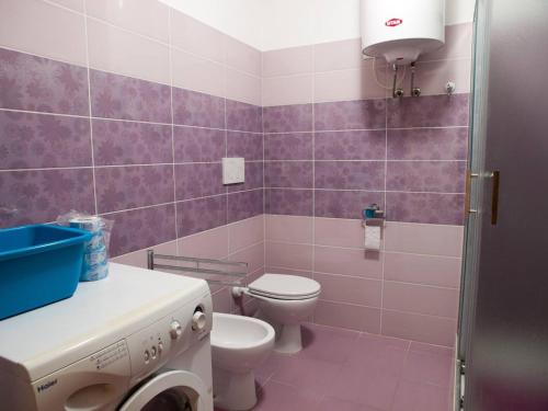 un bagno rosa con servizi igienici e lavandino di Appartamento vicino al mare a Piombino