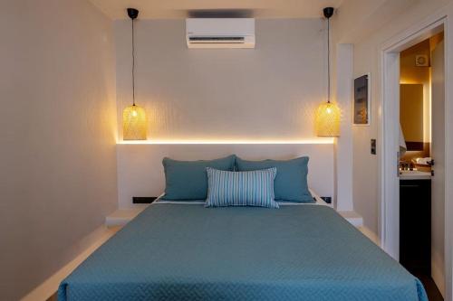 a bedroom with a blue bed with two pillows at Pearl Suites and Villa Tinos in Tinos Town