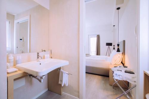 a white bathroom with a sink and a bed at Ah Porticcioli Boutique Apartments in San Felice del Benaco