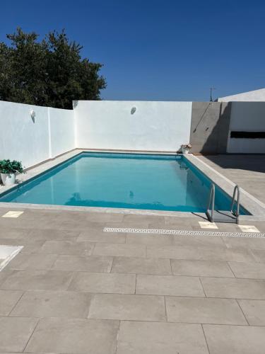 a swimming pool next to a white wall at Moinhos do Guadiana in Pedrógão