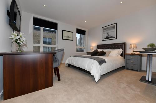 a bedroom with a bed and a desk and a television at Two-Bedroom Flat Chiswick in Kew Bridge