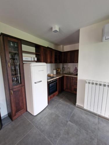 a kitchen with a white refrigerator and wooden cabinets at Vikendica Aleksandrović Meterize in Topola