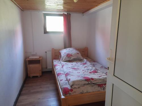 a small bedroom with a bed and a window at Cabana Ela&Mada in Gîrda de Sus
