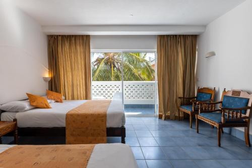 a hotel room with two beds and a balcony at Sun N Sand Beach Resort in Mombasa