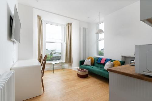 a living room with a green couch and a window at Stunning Central Penzance apartment with sea views in Penzance