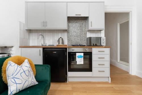 a kitchen with a green couch and a black refrigerator at Stunning Central Penzance apartment with sea views in Penzance