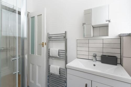 a white bathroom with a sink and a shower at Stunning Central Penzance apartment with sea views in Penzance