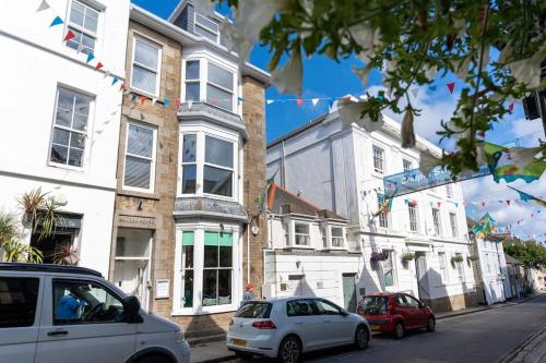 two cars parked in front of buildings on a street at Stunning Central Penzance apartment with sea views in Penzance